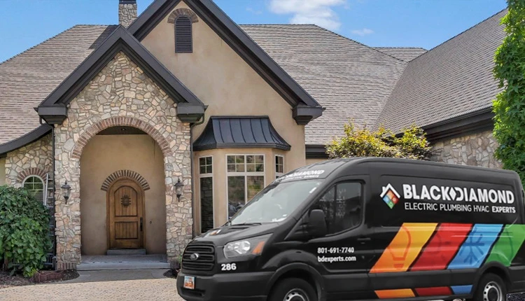 A luxury stone house with an arched wooden door and large windows, set against a clear blue sky. A Black Diamond service van is parked in front.