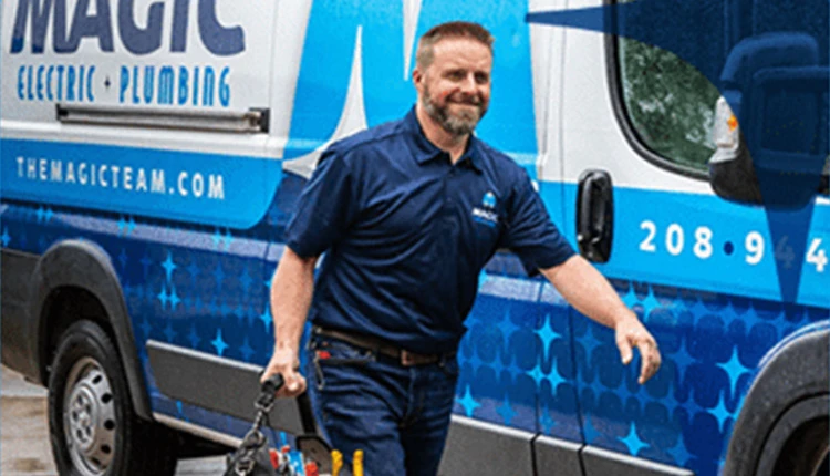 A smiling technician in a blue uniform walks, holding tools, in front of a branded van reading 